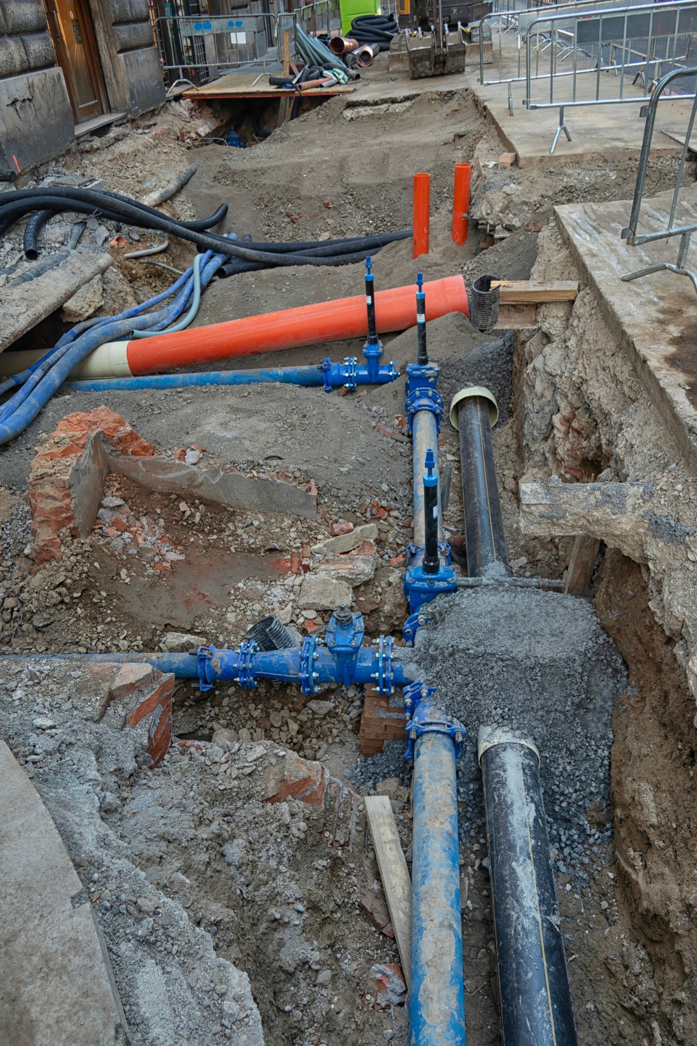 A bunch of pipes are laying in the dirt on the ground.