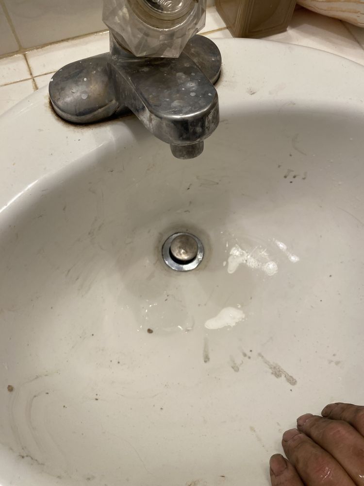 A person is washing their hands in a bathroom sink.