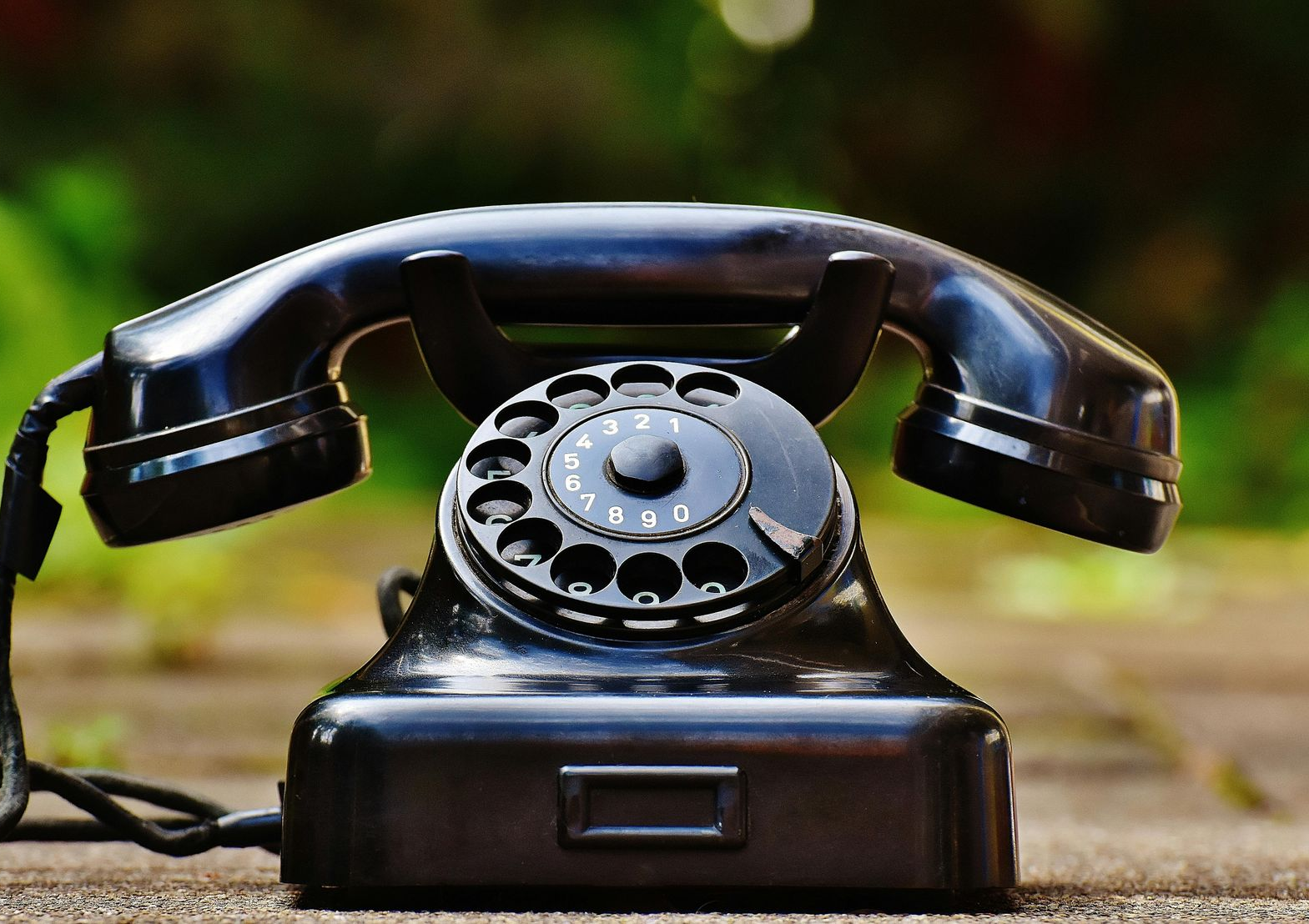 Black rotary phone outdoors.