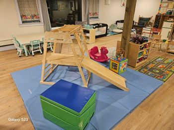 A wooden playground is sitting on top of a blue mat in a room.