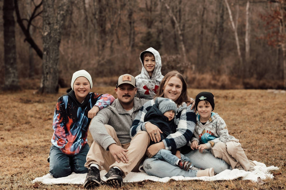 A family is posing for a picture while sitting on the ground.