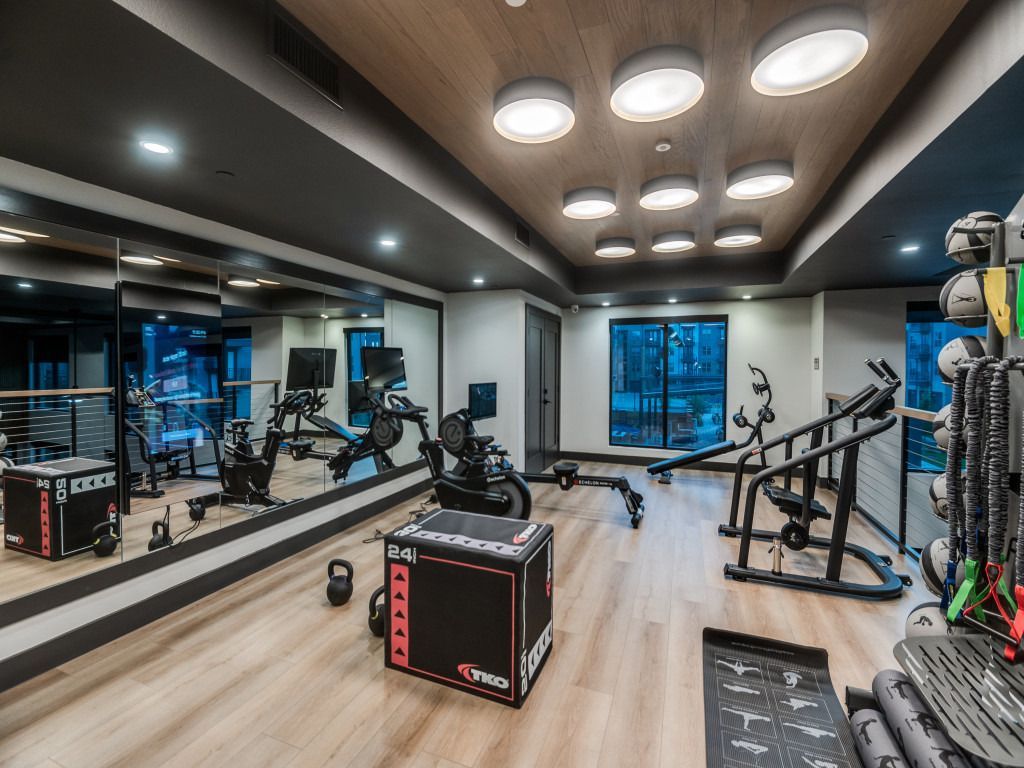 A large gym with a lot of equipment and a lot of mirrors.