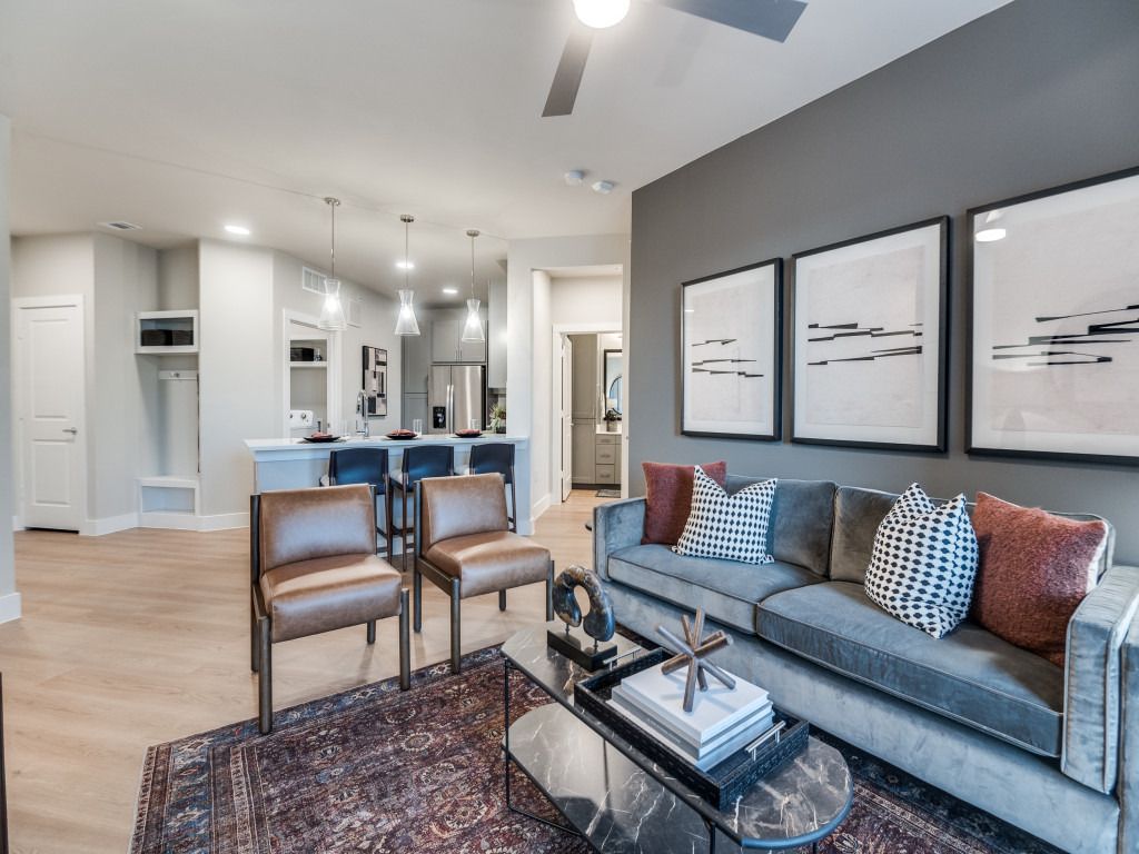 A living room with a couch , chairs , a coffee table and a ceiling fan.