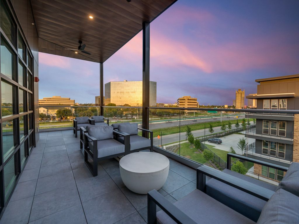 A balcony with chairs and a table overlooking a city.