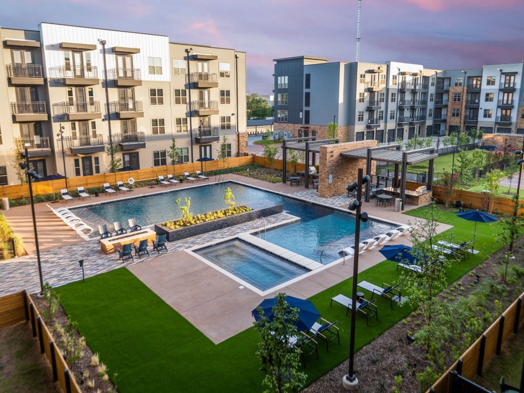 An aerial view of a large swimming pool in front of a large apartment building.