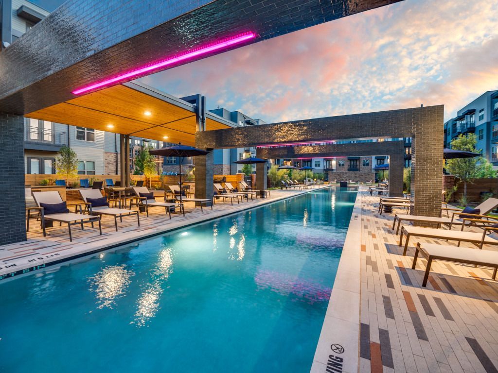 A large swimming pool surrounded by chairs and tables in a building.