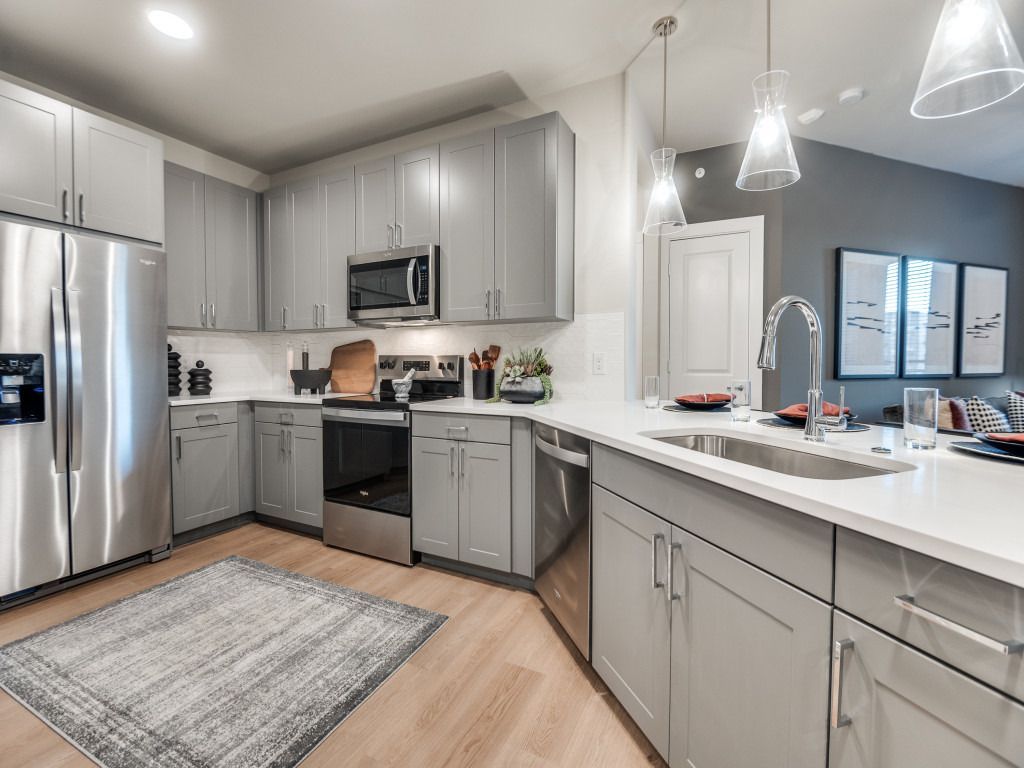 A kitchen with gray cabinets and stainless steel appliances.