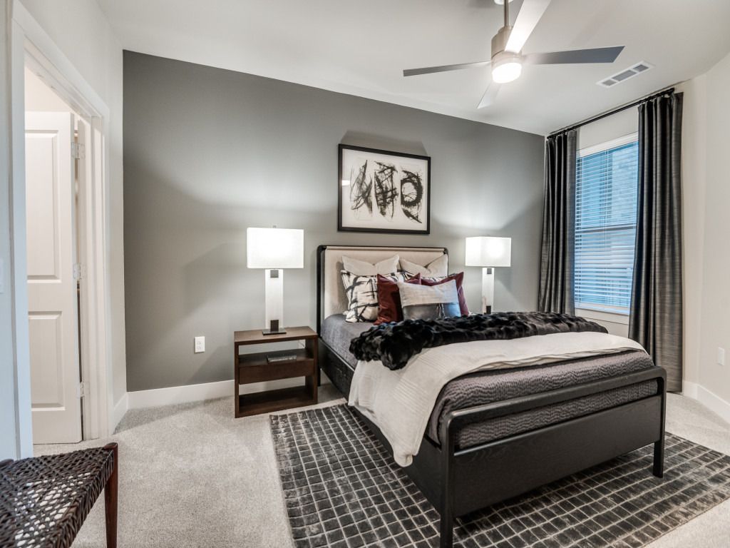 A bedroom with a bed , nightstands , lamps and a ceiling fan.