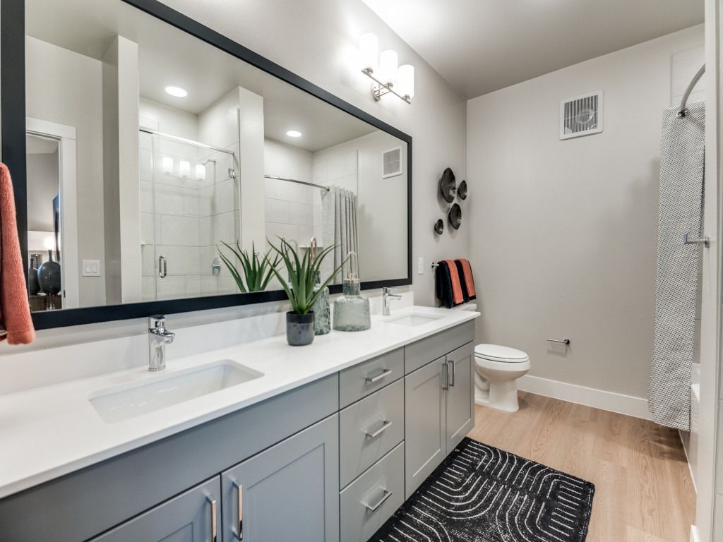 A bathroom with two sinks , a toilet , and a large mirror.