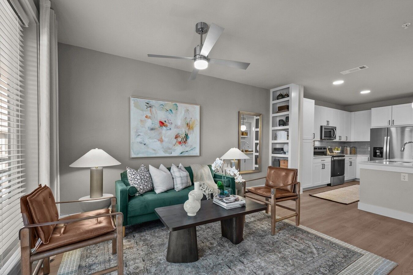 A living room with a green couch , two chairs , a coffee table and a ceiling fan.