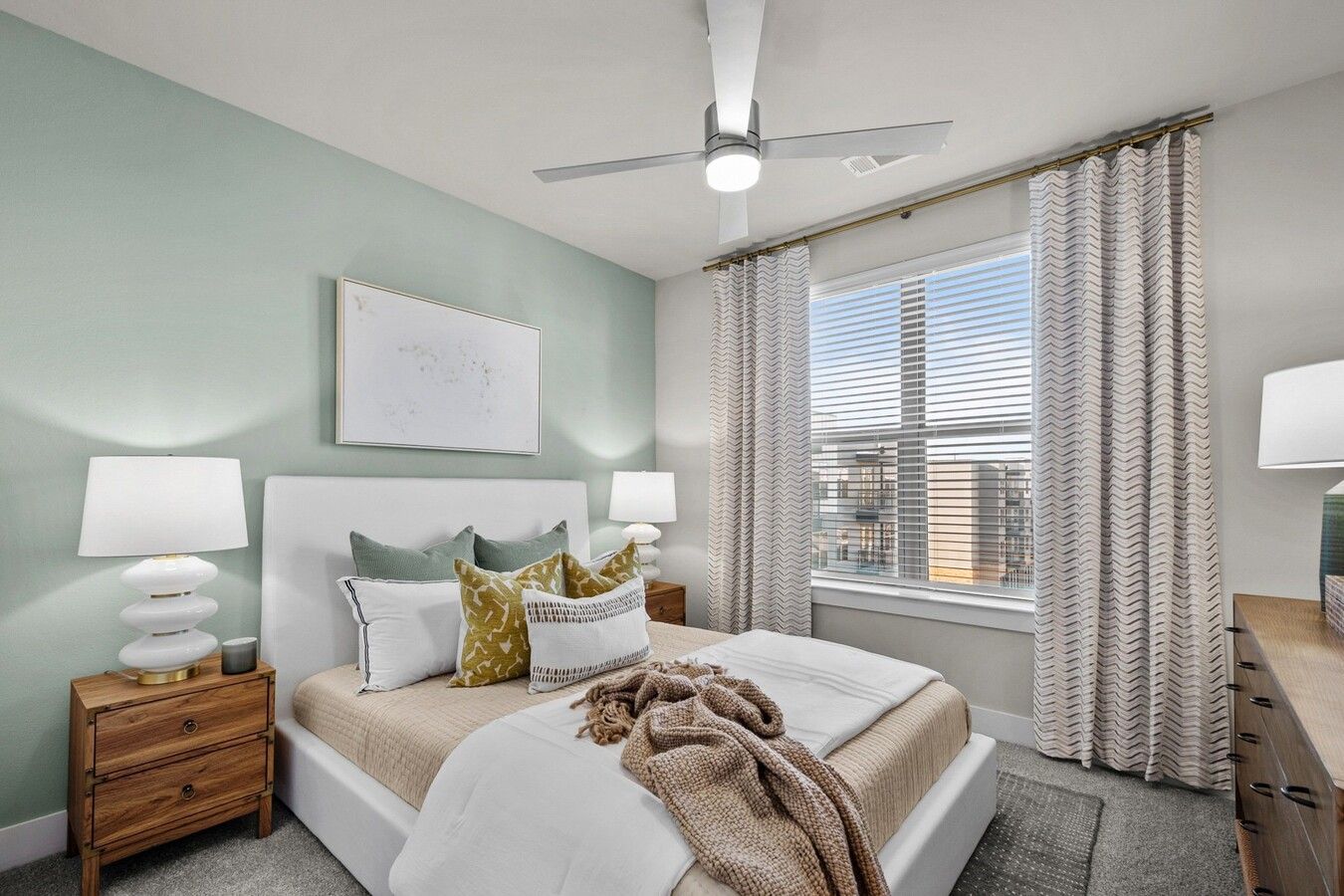 A bedroom with a bed , nightstand , lamps and a ceiling fan.