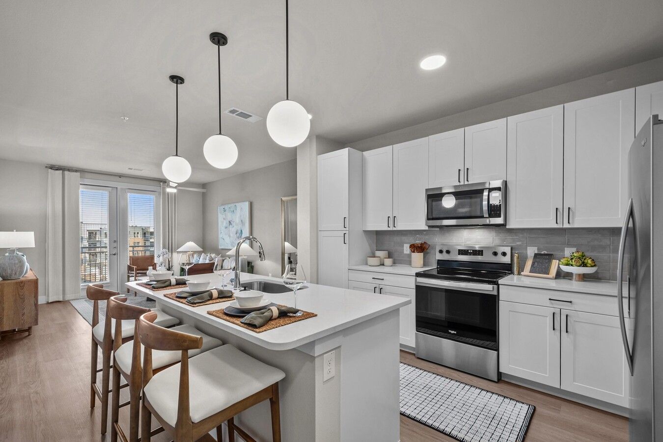 A kitchen with white cabinets , stainless steel appliances , and a large island.