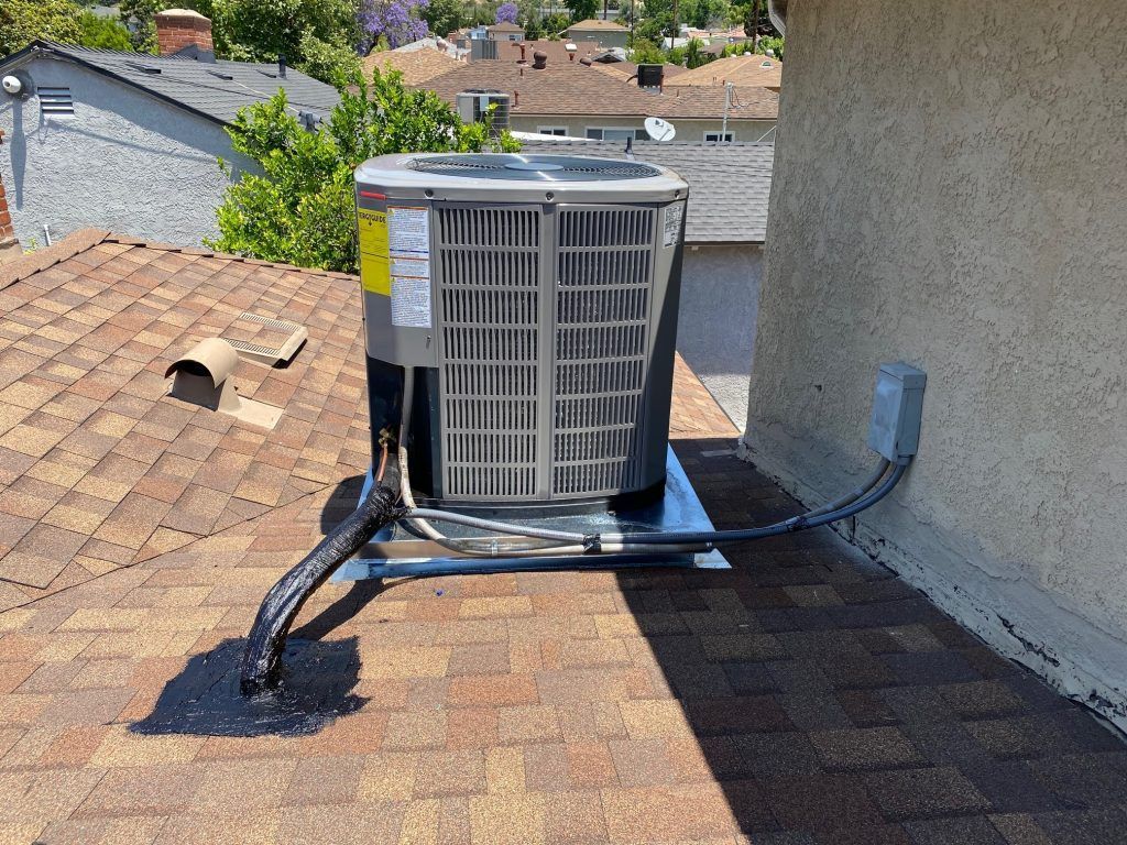 AC unit on a rooftop with power and coolant lines attached.
