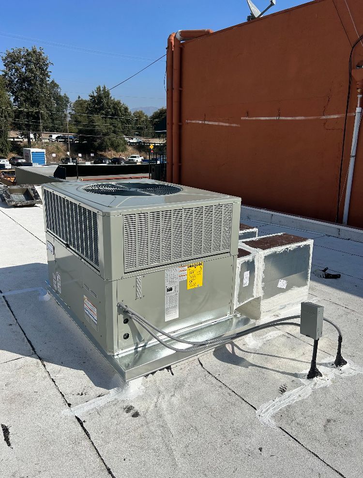 HVAC unit on a flat roof against a burnt orange building; blue sky overhead.