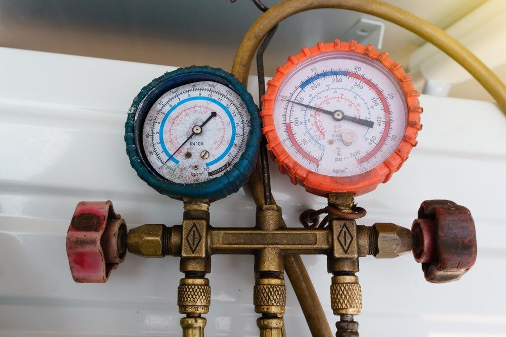 HVAC manifold gauge set with blue and red gauges, connected to hoses.