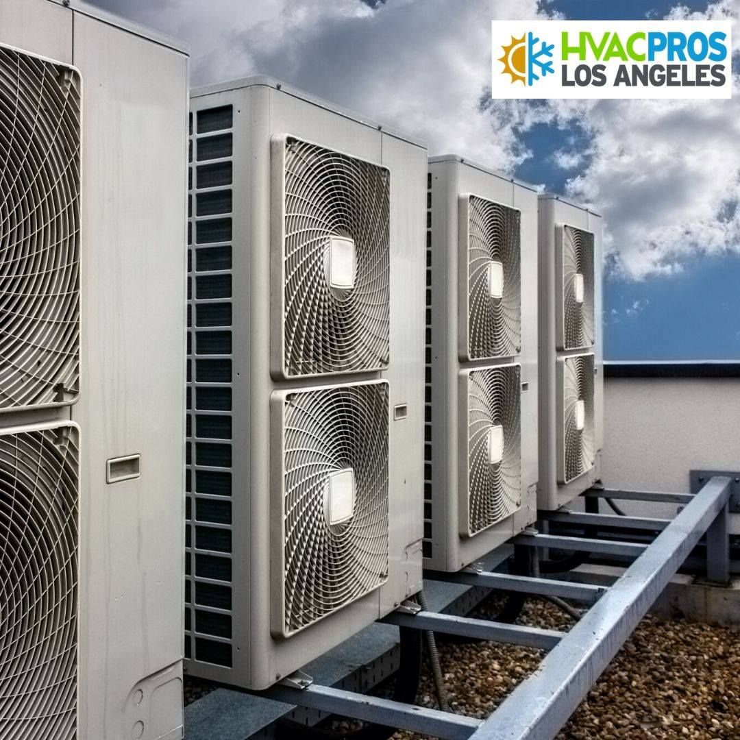 HVAC units lined up on a rooftop with a partly cloudy sky in the background.