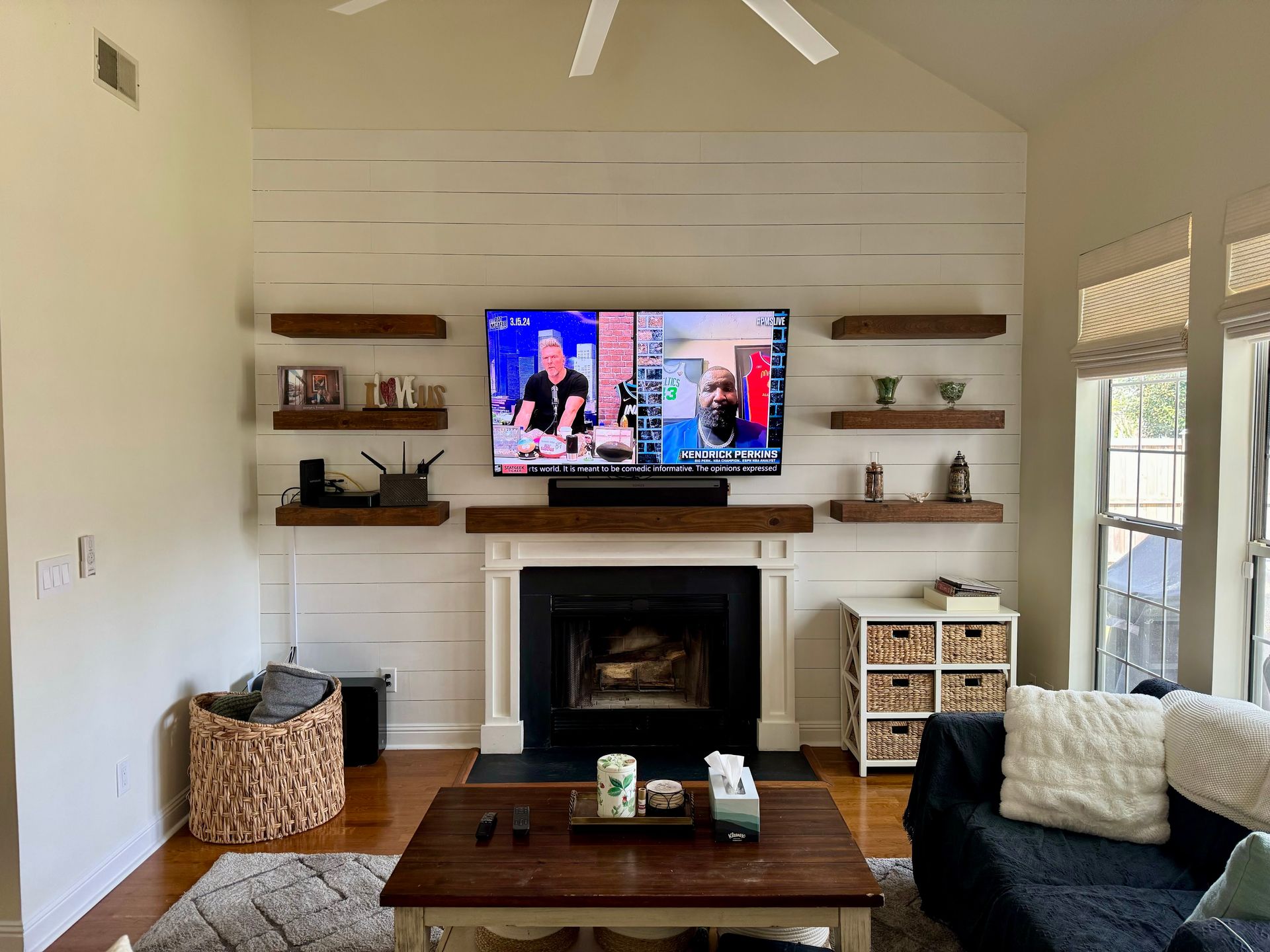 Bright living room with a fireplace, TV, coffee table, and built-in shelves under a vaulted ceiling.