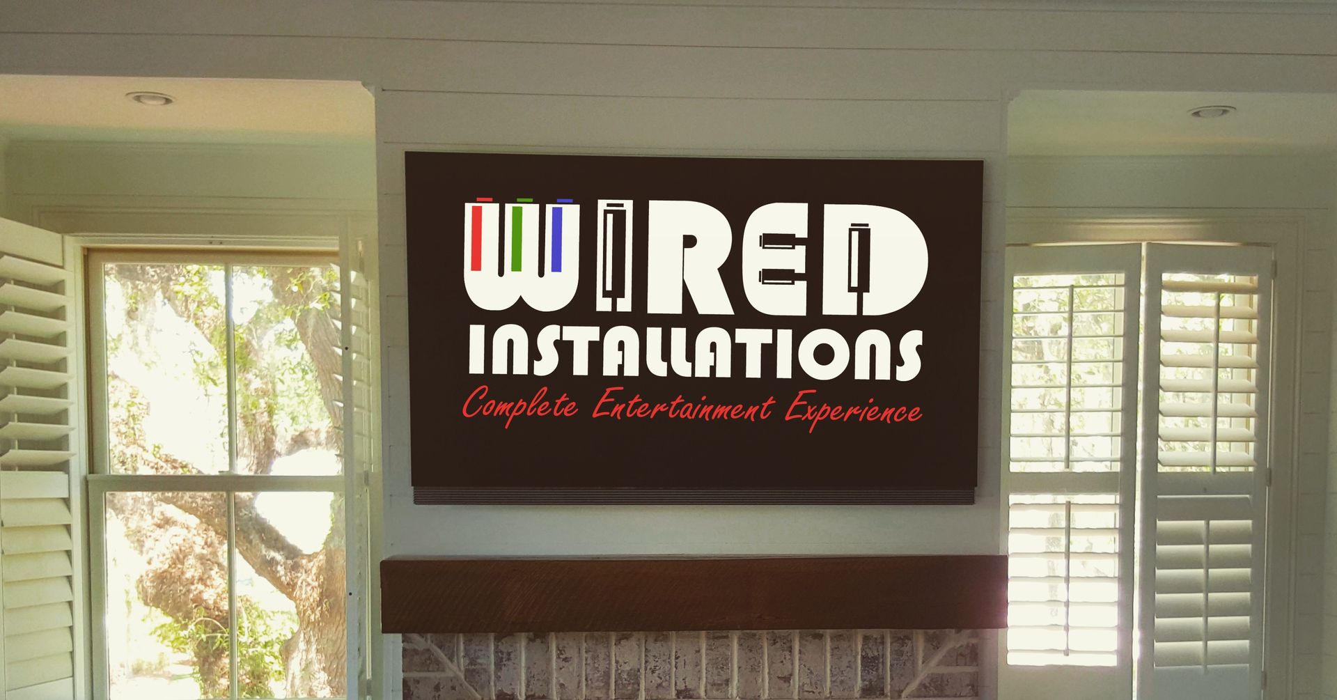 Wired Installations logo sign above a fireplace in a bright room with windows