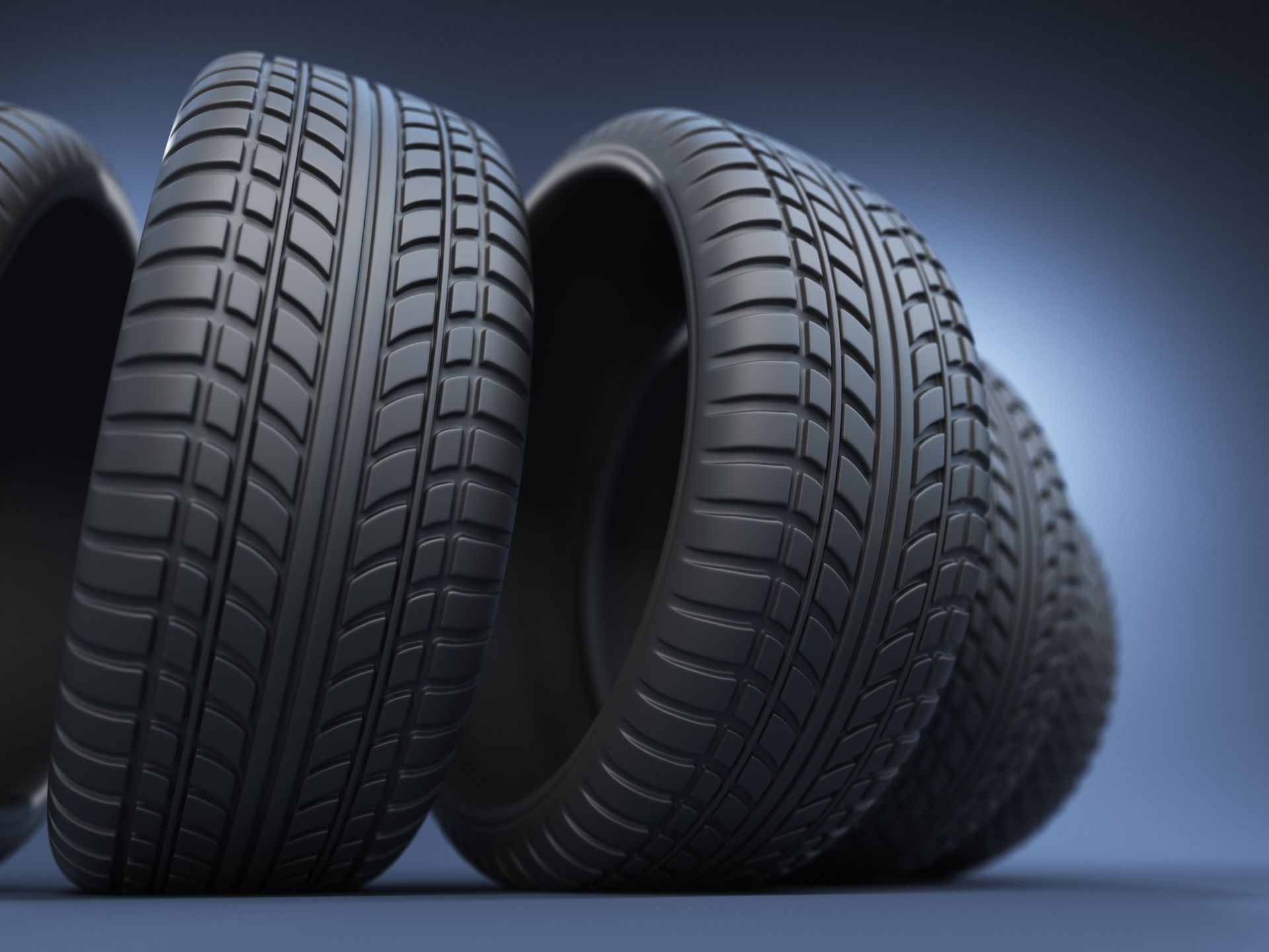 A row of black rubber car tires standing upright against a dark blue background.