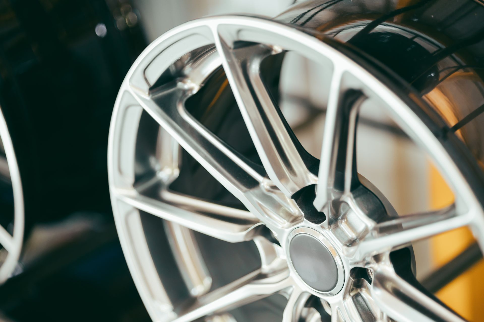 A close-up, angled view of a sleek, silver multi-spoke alloy car wheel against a dark background.