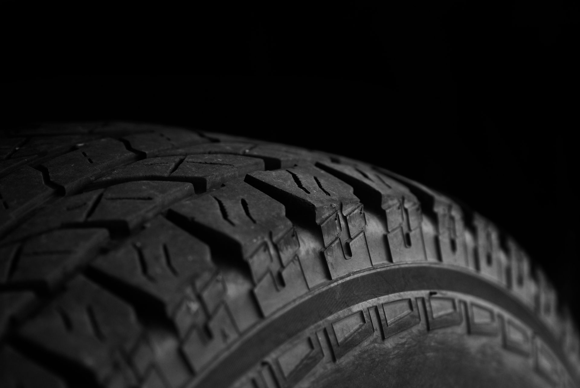 Close-up of a black tire tread against a dark, minimalist background.