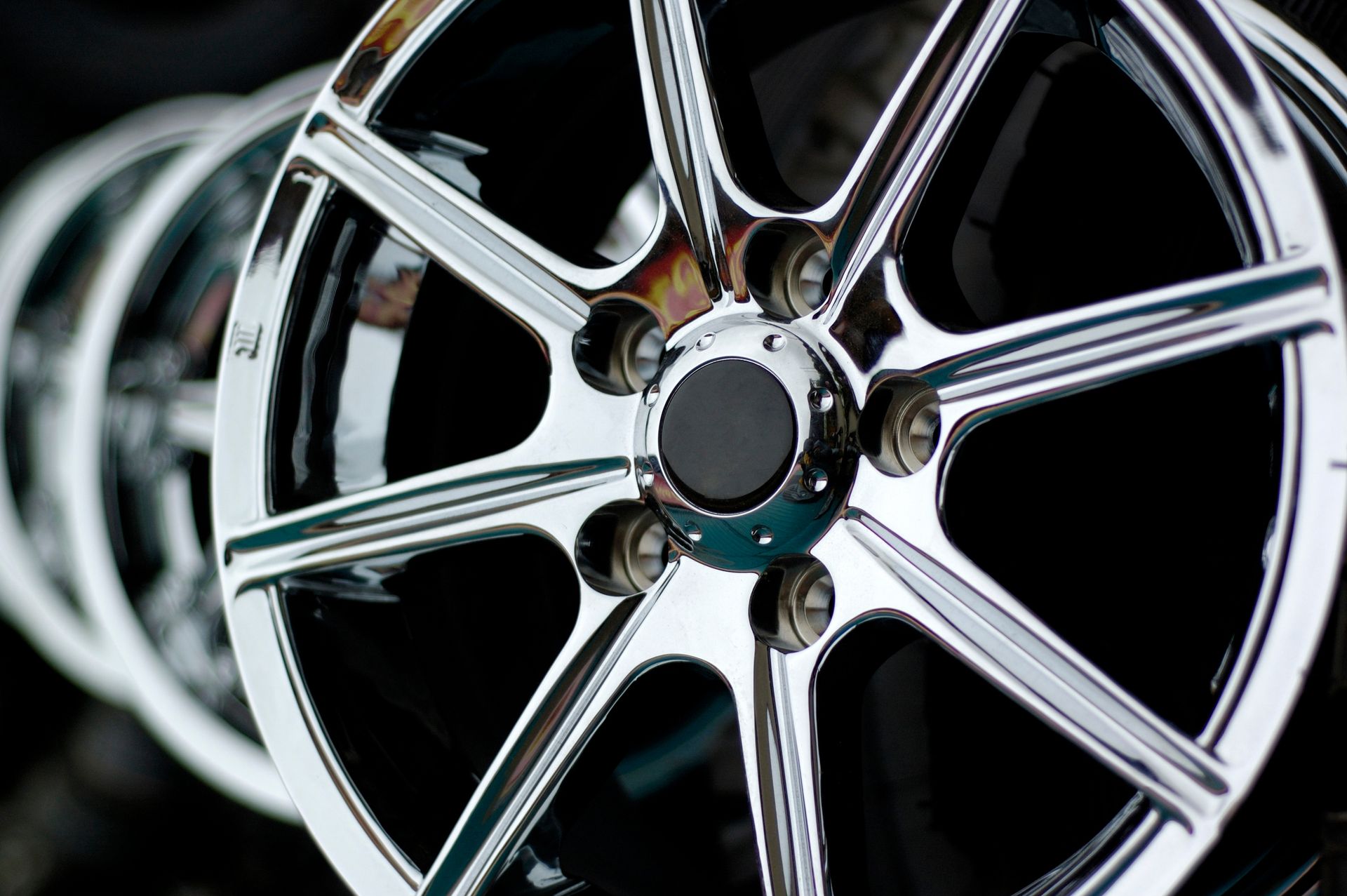 A close-up, angled view of a series of polished chrome car wheels with a multi-spoke design.