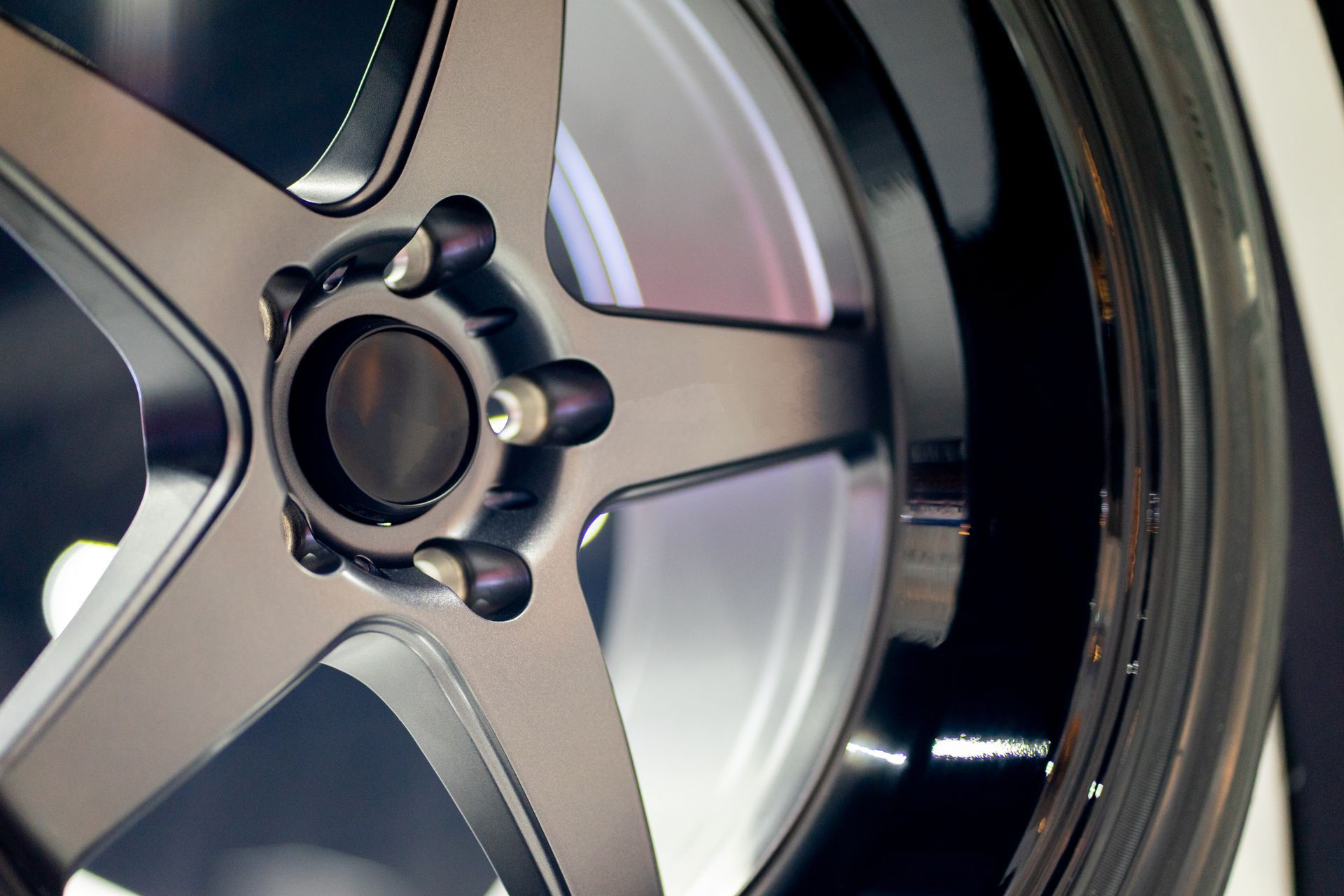 Close-up of a matte dark grey, five-spoke alloy car wheel with a glossy black rim edge.