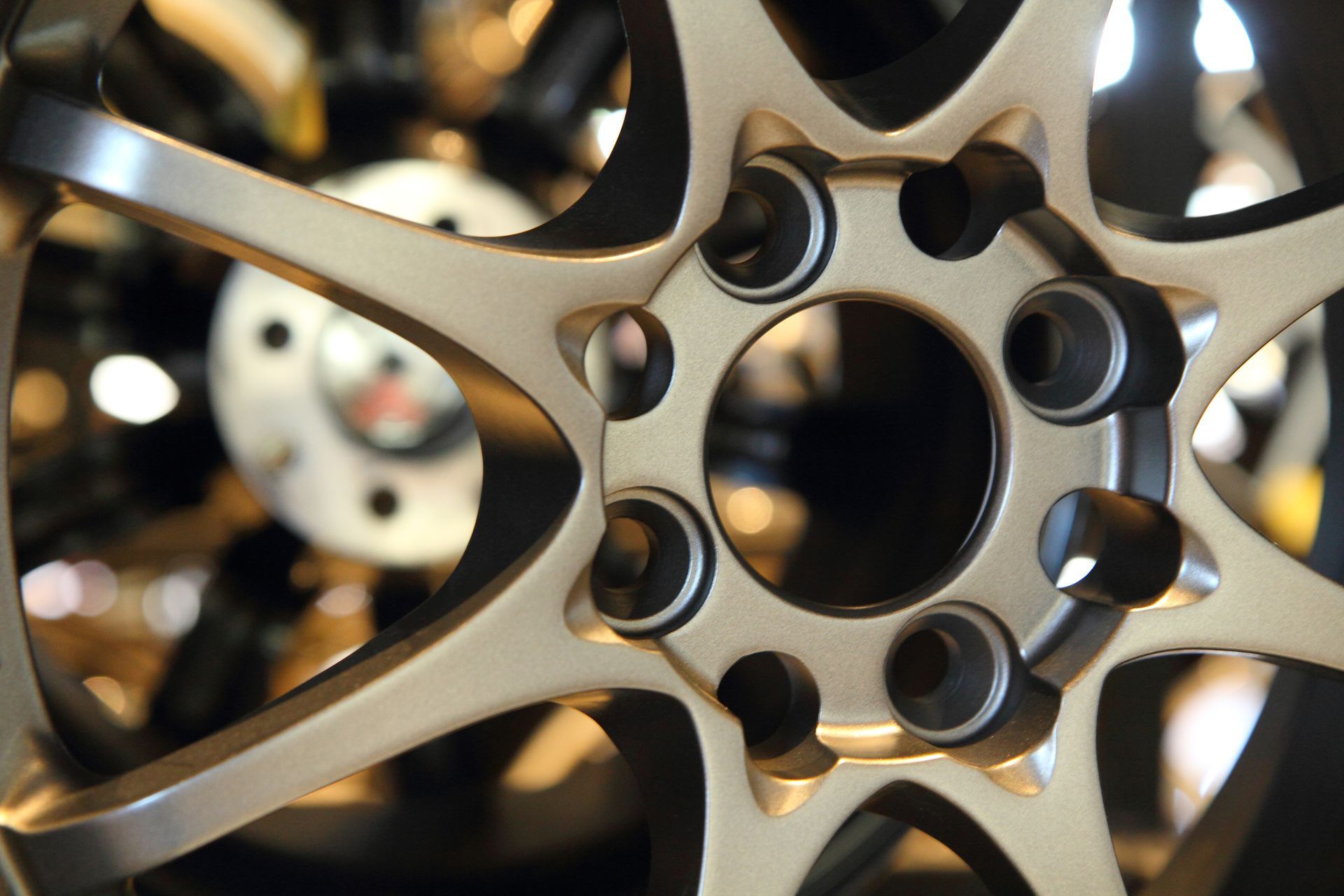 A close-up, angled view of a bronze-colored, multi-spoke alloy car wheel rim with a central hub hole.