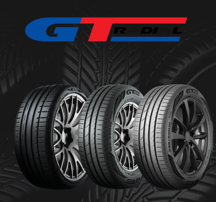 A close-up, angled view of a black car tire with a distinct chevron-patterned tread design.