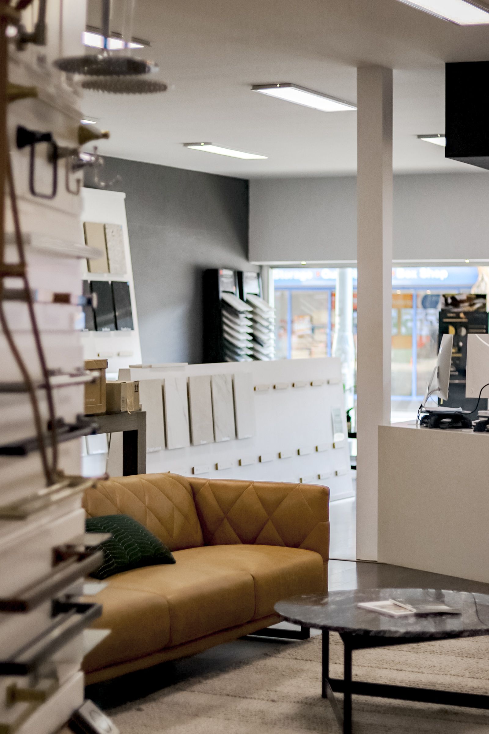 Interior showroom with tan sofa, displays, and a low table.