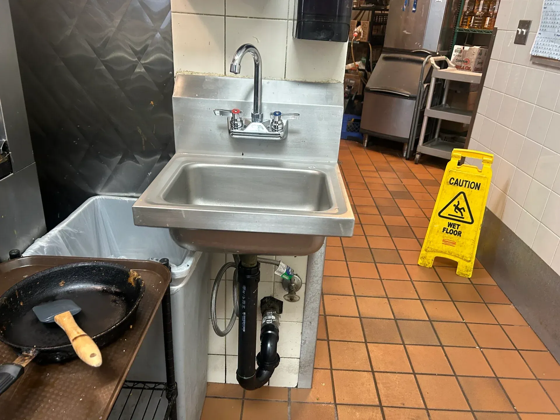 A kitchen with a sink and a yellow caution sign