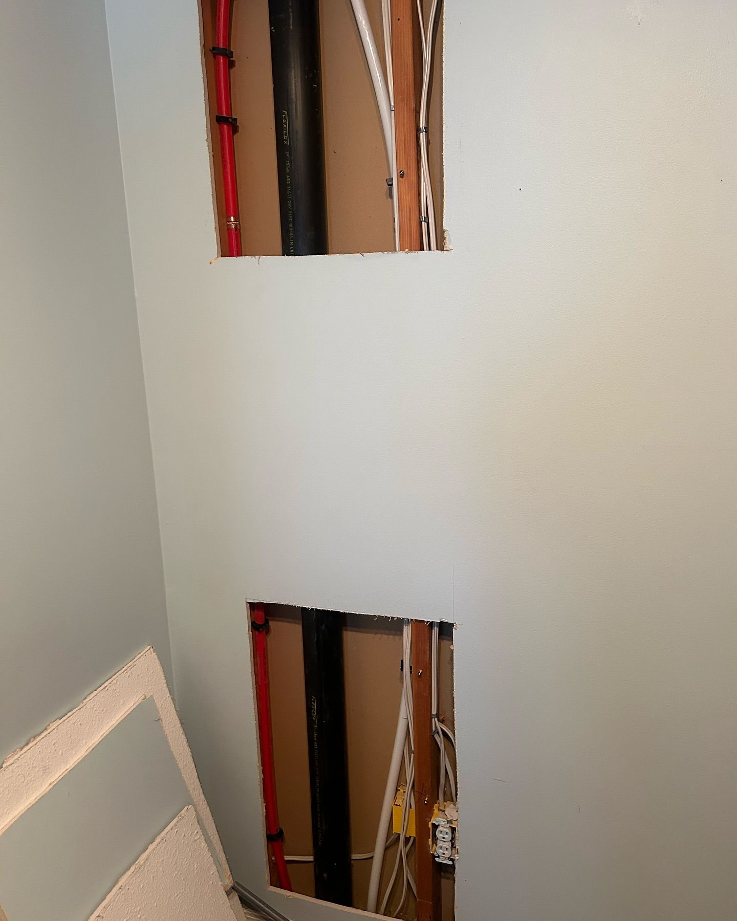 A room with a hole in the wall and pipes coming out of it.