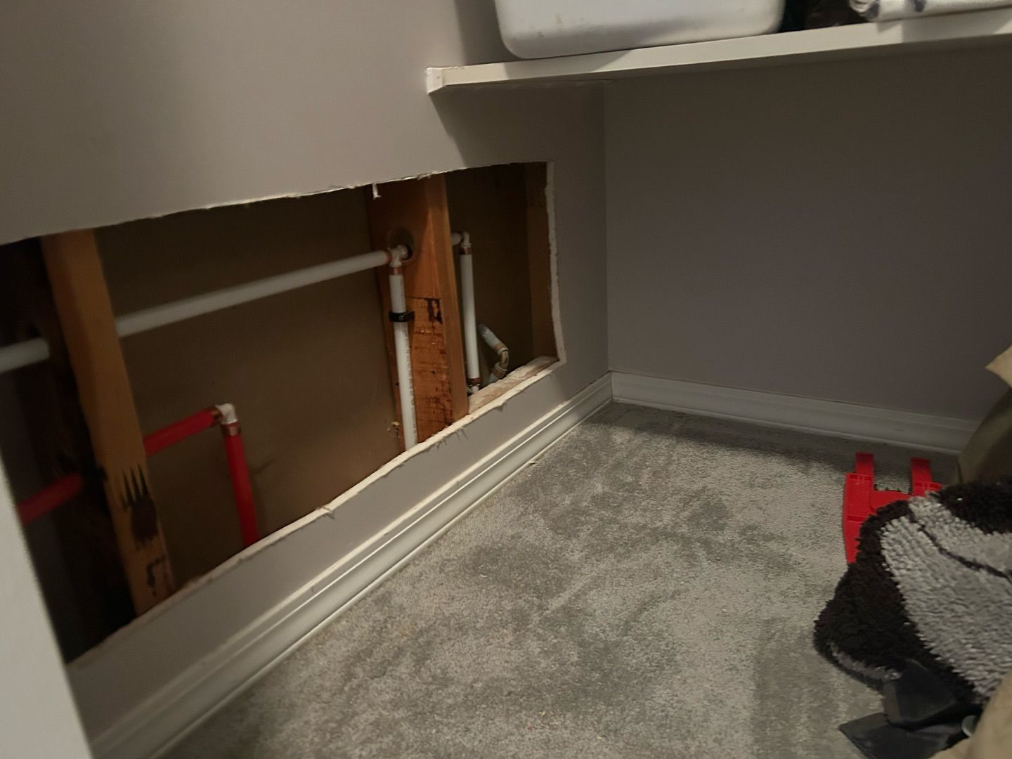 A person is standing in a room with a hole in the wall.