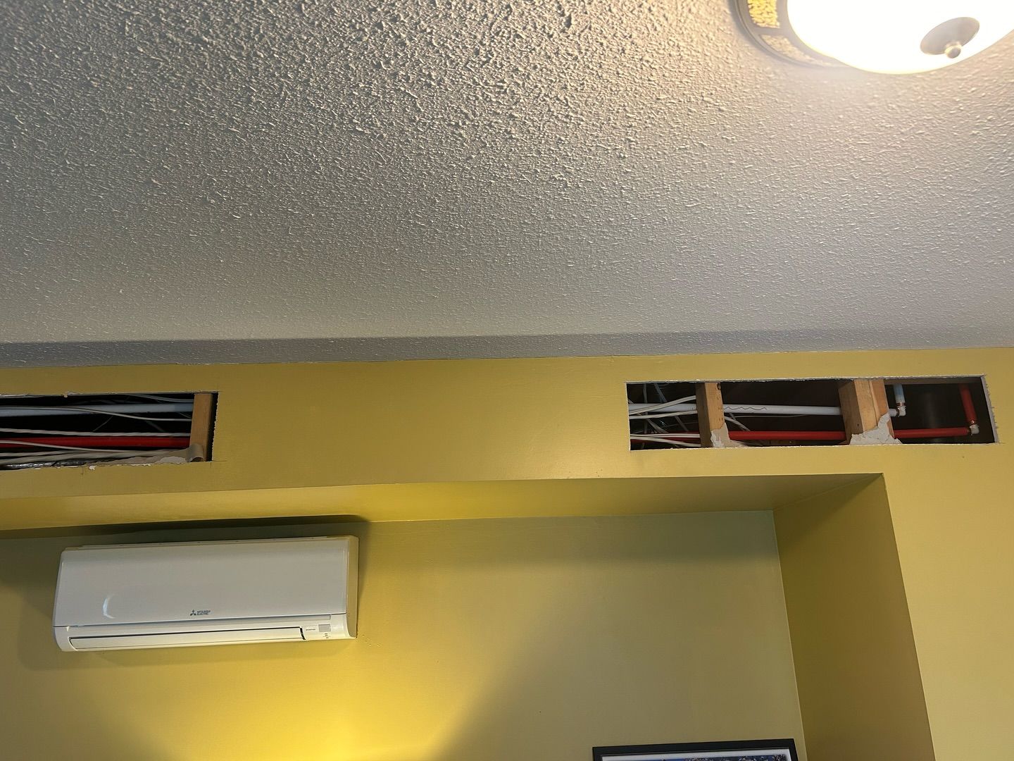 A room with yellow walls and a white air conditioner on the wall.