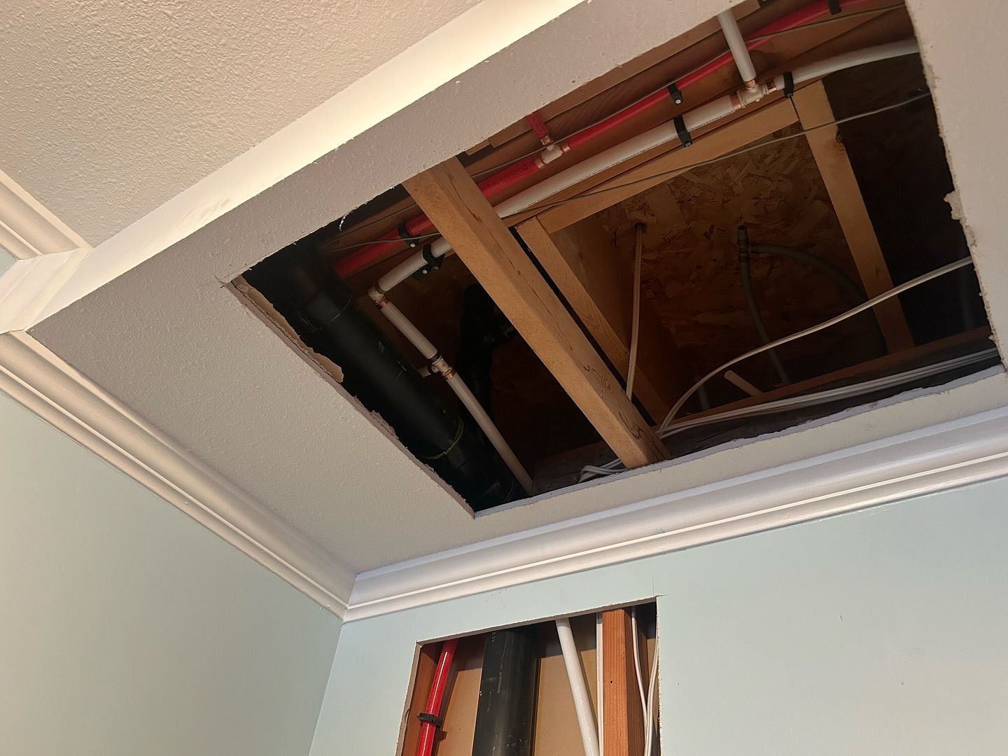 A hole in the ceiling of a room with pipes coming out of it