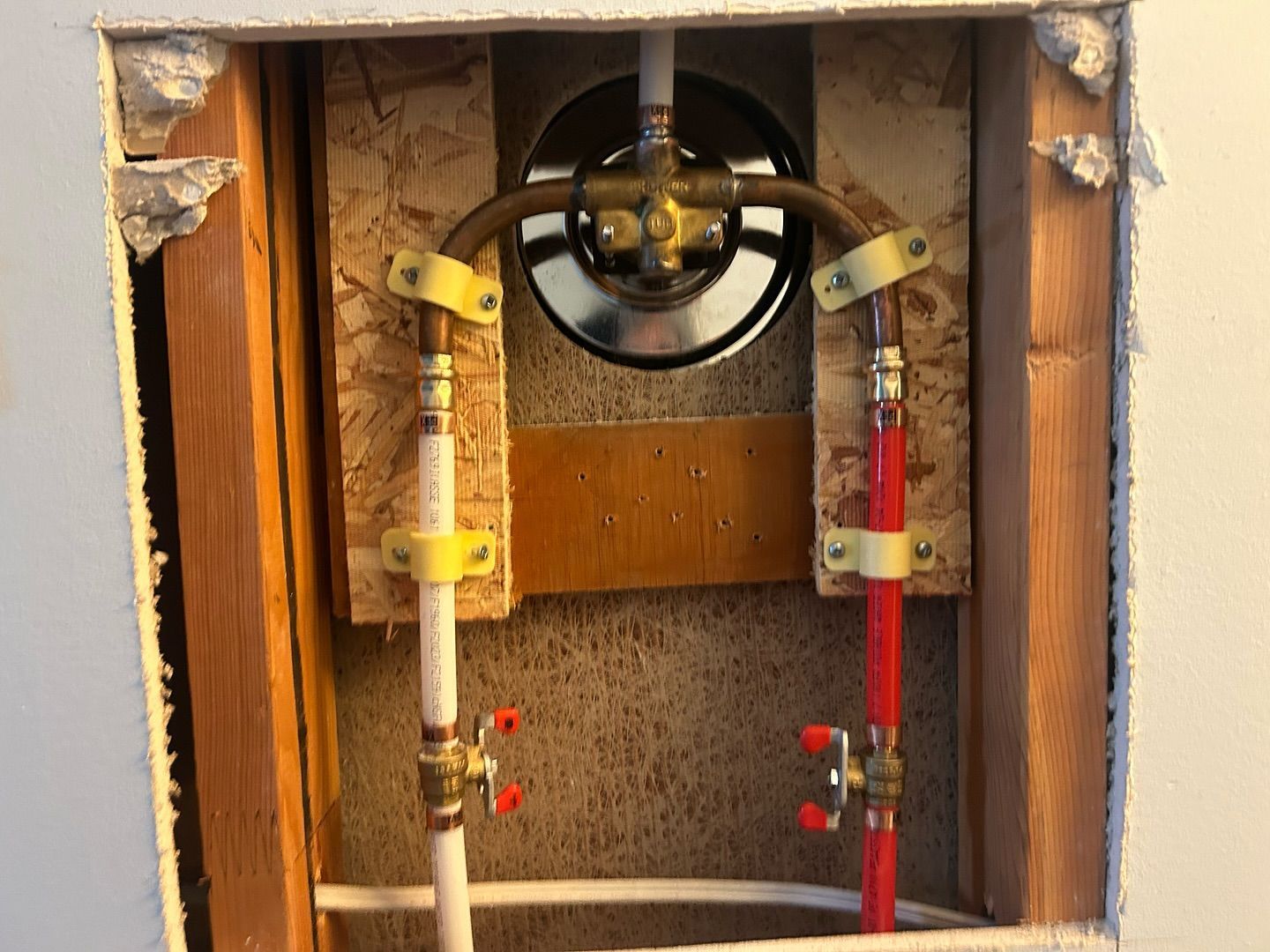 A hole in the wall with a valve and pipes in it.