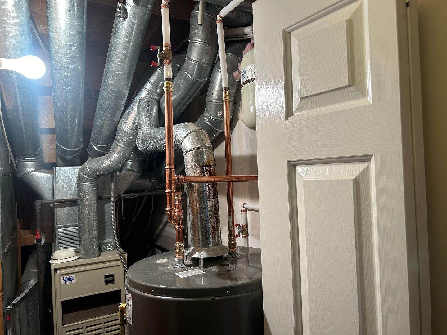 A room with a water heater , air conditioner , and pipes.