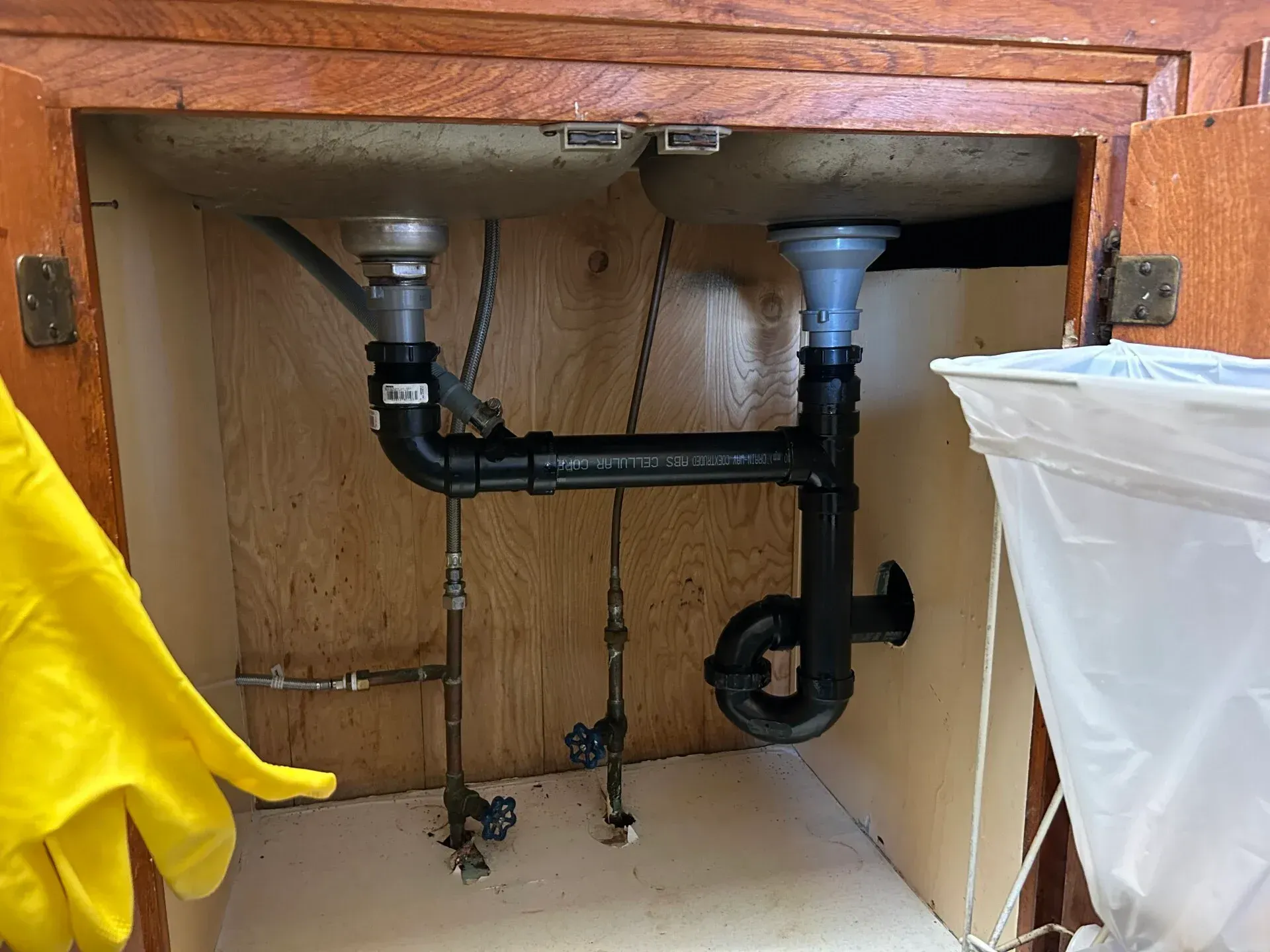A sink is sitting under a wooden cabinet.