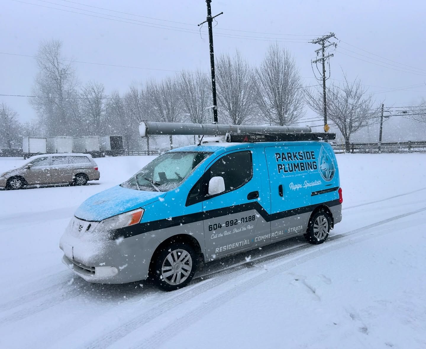 A blue and gray van is driving through the snow.
