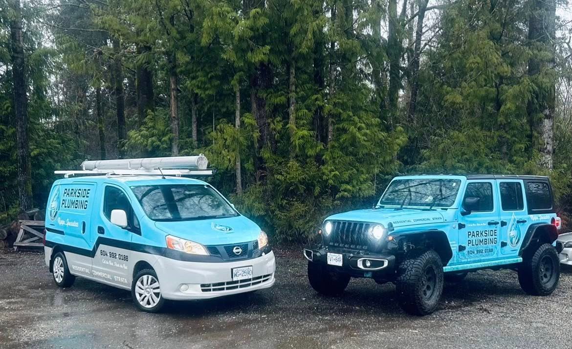 Two blue vans and a jeep are parked next to each other in a parking lot.