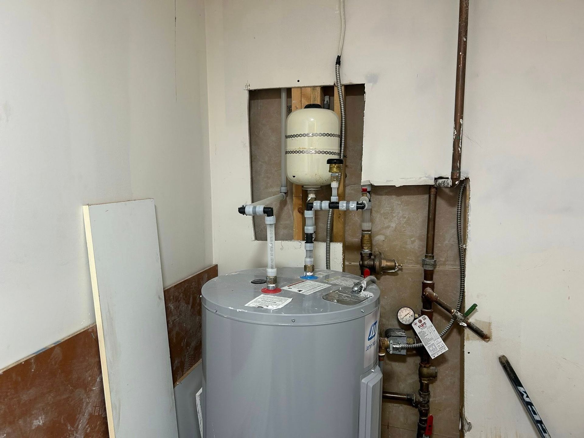 A water heater is sitting in a room next to a wall.