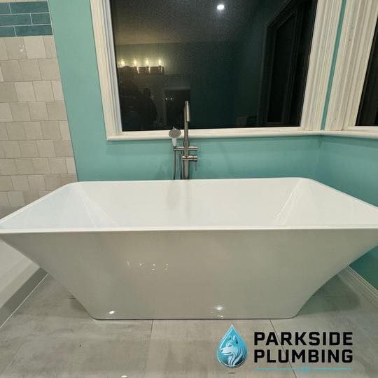 A white bathtub is sitting in a bathroom next to a window.