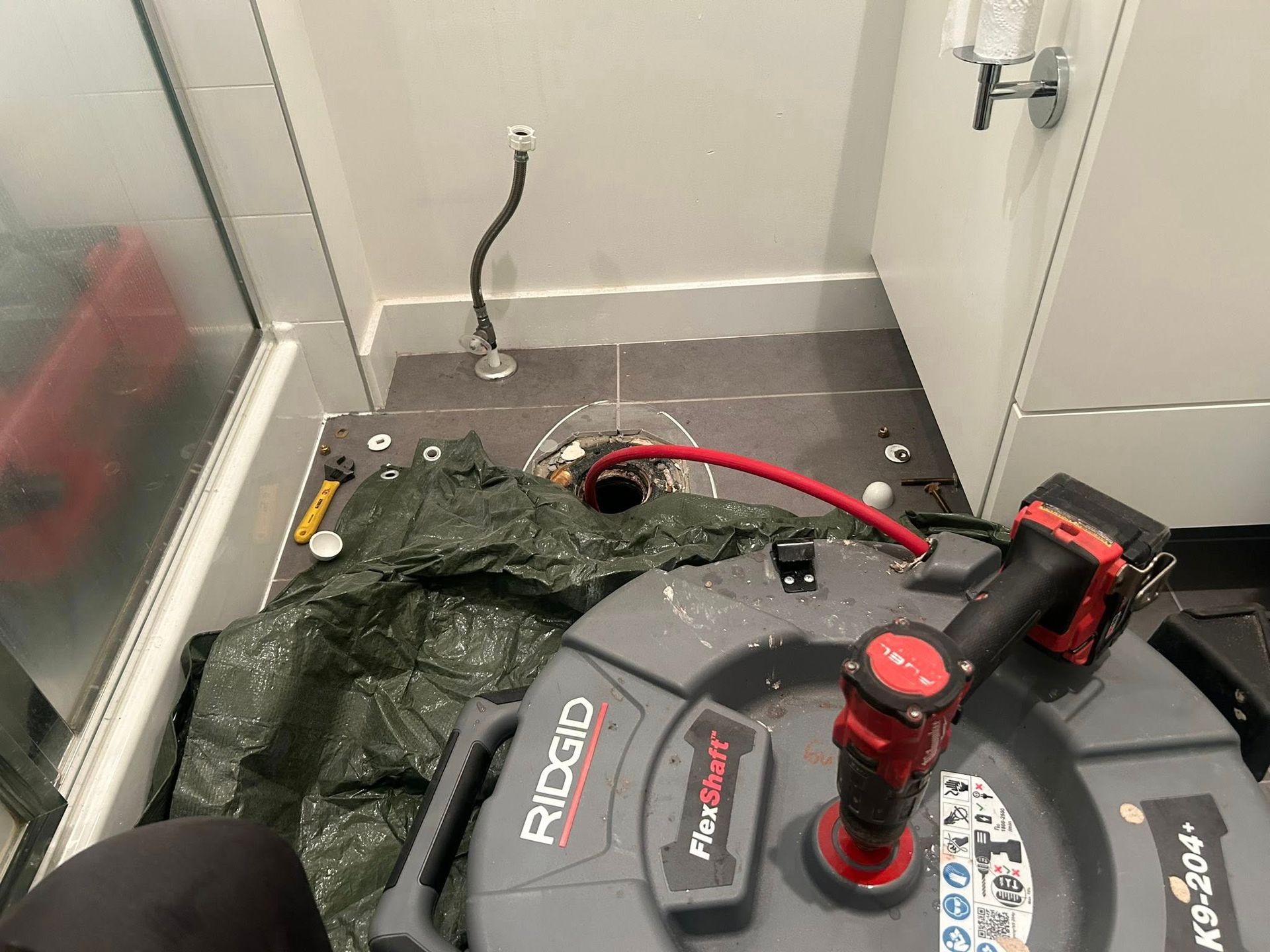 A person is using a machine to fix a drain in a bathroom.