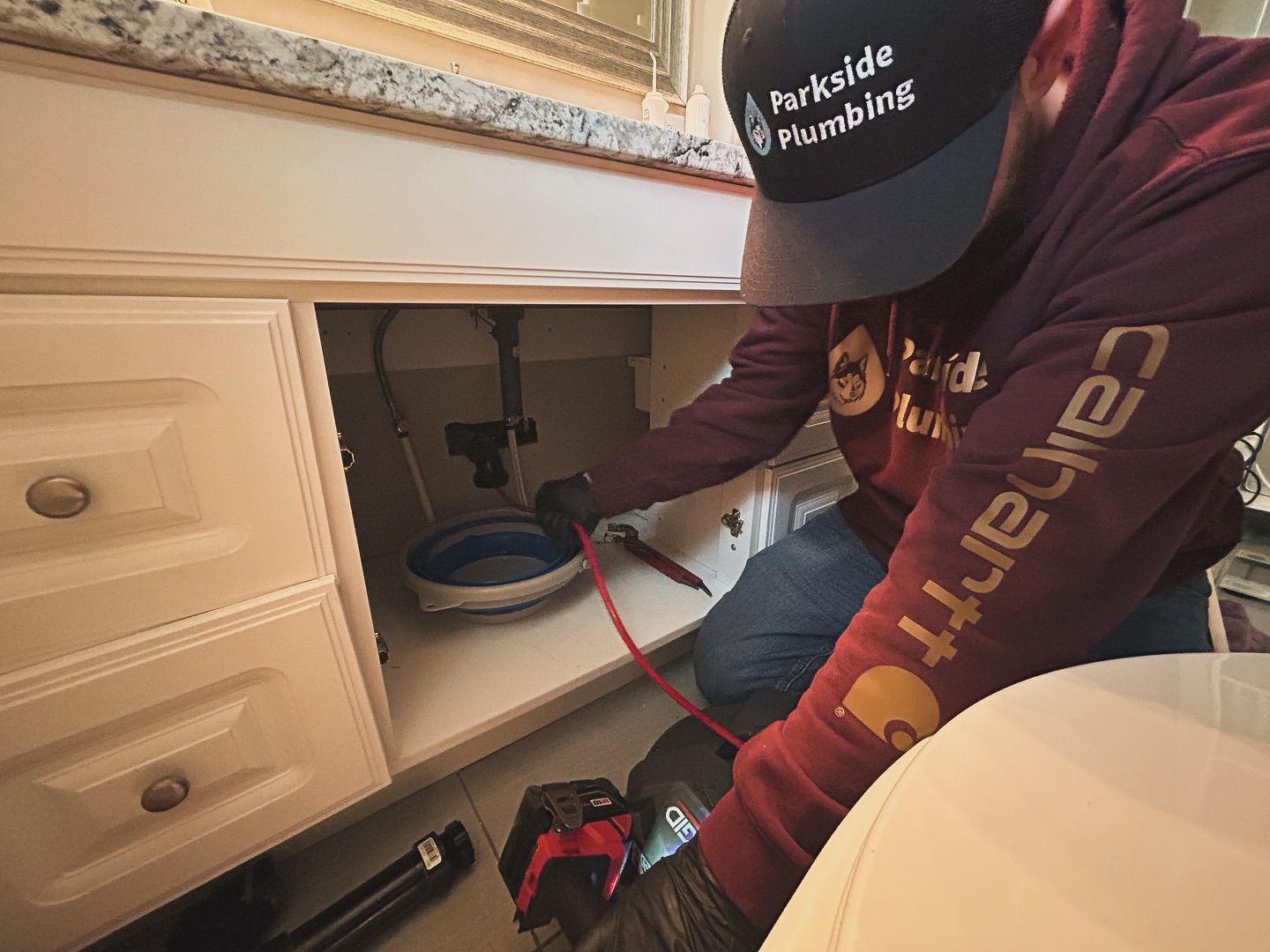 A man is fixing a sink in a bathroom.