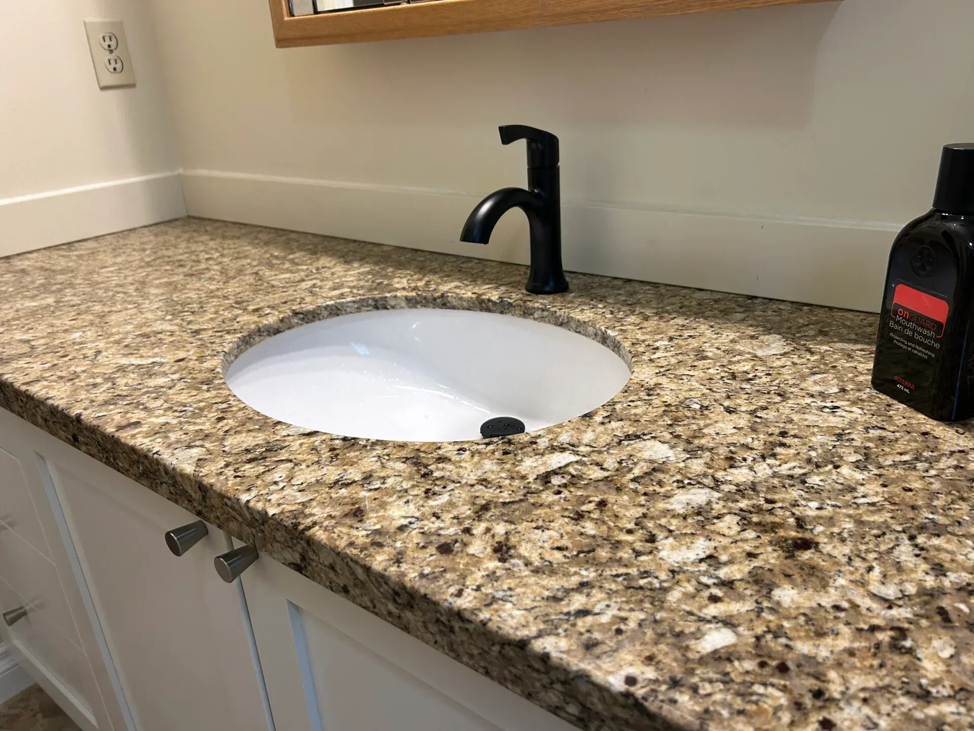 A bathroom sink with a granite counter top and a black faucet.