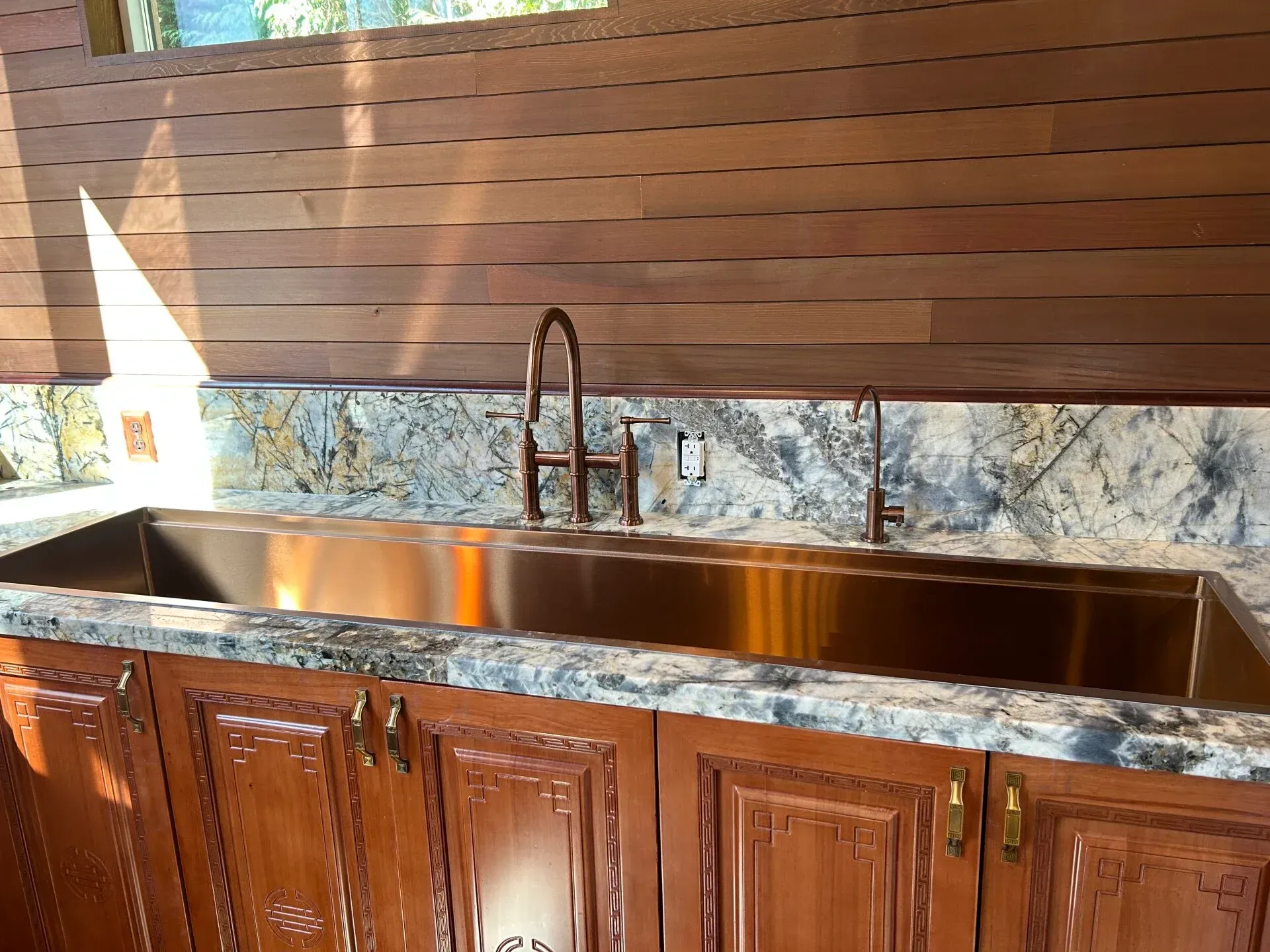 A kitchen with a stainless steel sink and wooden cabinets