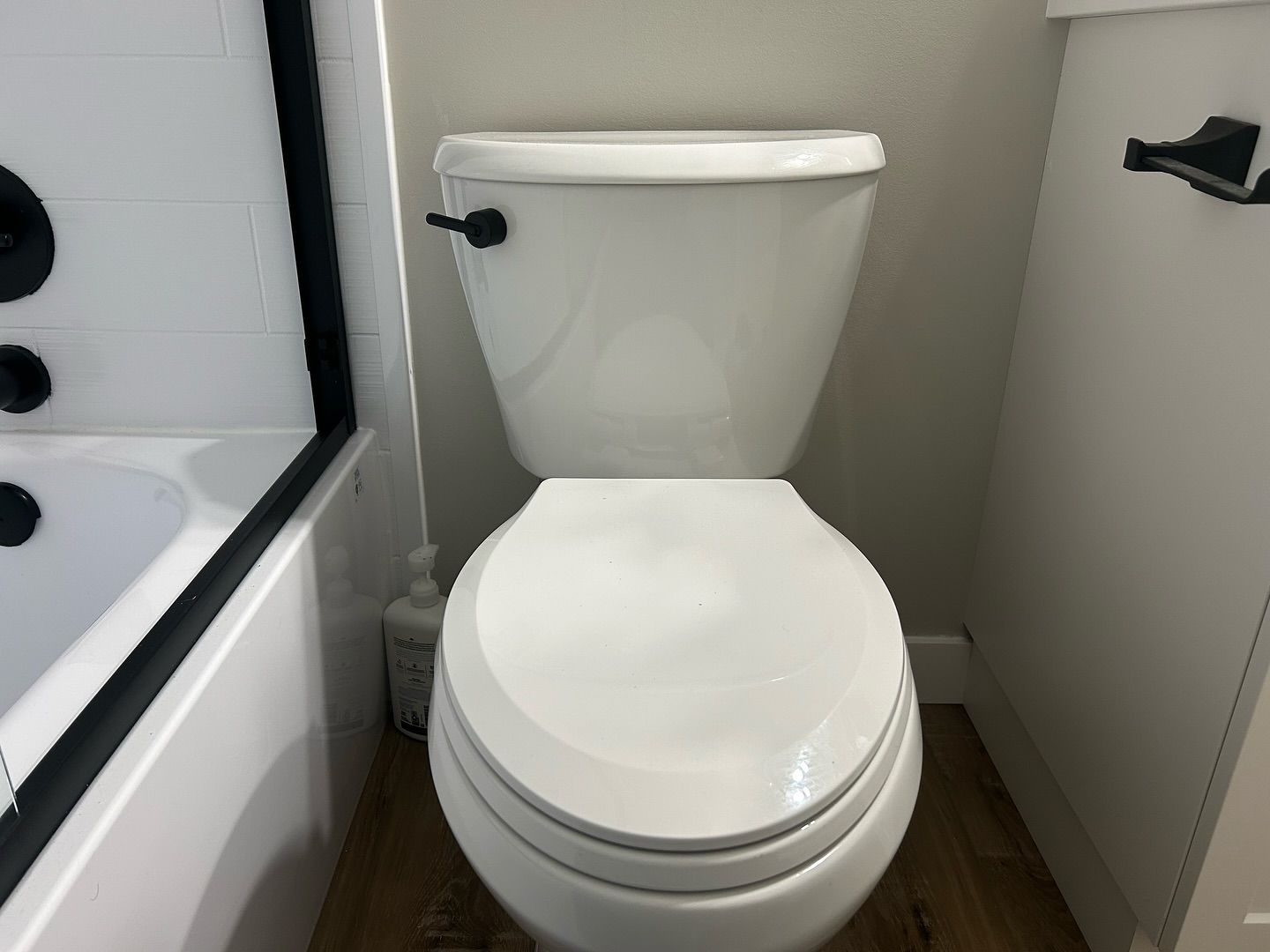 A white toilet is in a bathroom next to a bathtub.