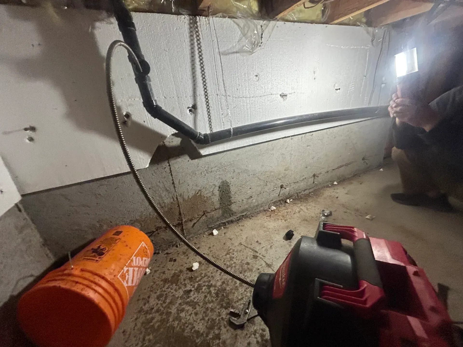 A vacuum cleaner is being used to clean a pipe in a basement.