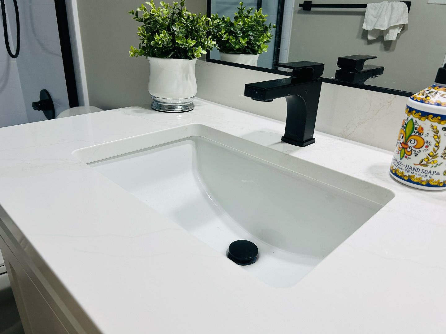 A bathroom sink with a black faucet and a vase of flowers on the counter.