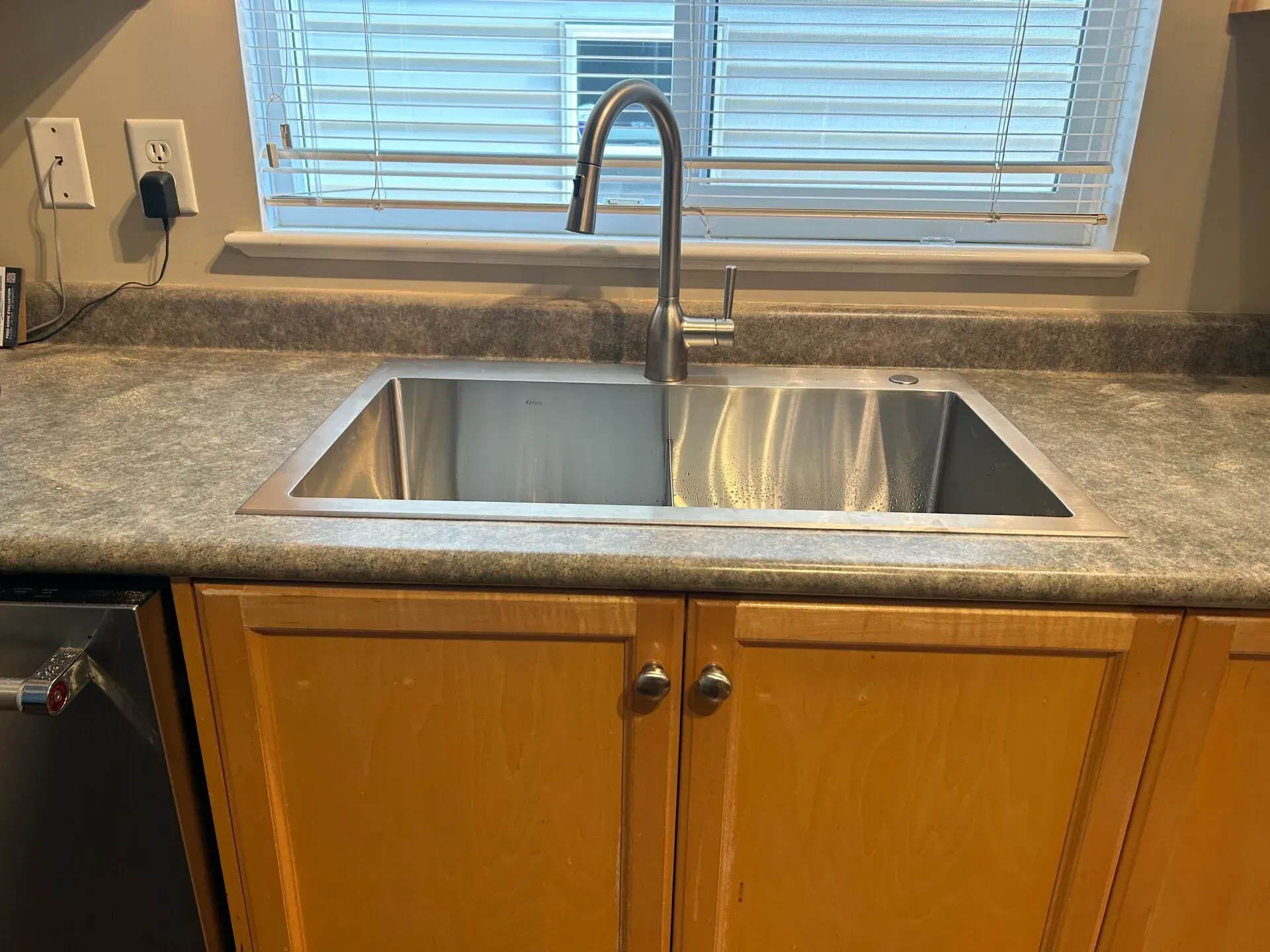 A kitchen sink is sitting on a counter next to a window.